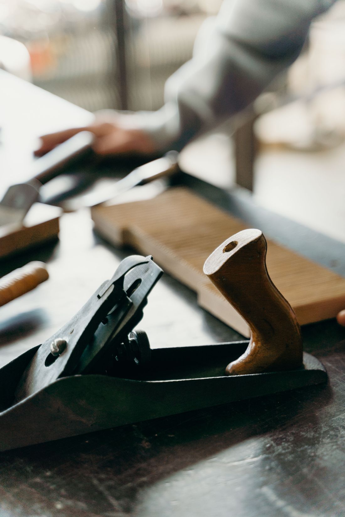 Hand plane resting on a workbench beside a wood panel
